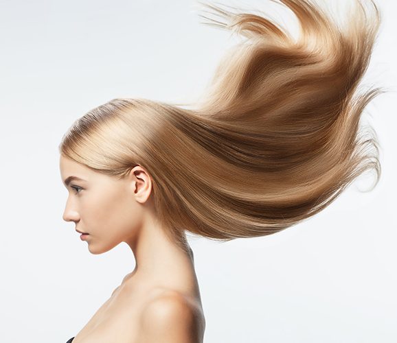 Beautiful model with long smooth, flying blonde hair isolated on white studio background. Young caucasian model with well-kept skin and hair blowing on air. Concept of salon care, beauty, fashion.